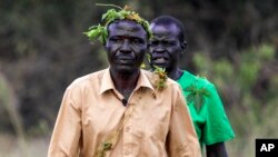 John Gafabusa, followed by Abiri Ntarwete, walks from the Mutyona natural sacred site near Buliisa, Uganda, Aug. 3, 2023. Bagungu people worry that TotalEnergies projects will deteriorate the spiritual power of at least 32 sacred natural sites in Buliisa.