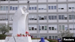 Una estatua del difunto Papa Juan Pablo II se encuentra afuera del Hospital Gemelli, donde el Papa Francisco ha ido para continuar el tratamiento de una bronquitis persistente en Roma, Italia, el 17 de febrero de 2025.