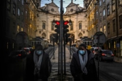 A woman wearing a face mask is reflected in a shop window while walking in Lisbon as Portugal entered a fresh lockdown over a surge in coronavirus cases.