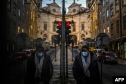 A woman wearing a face mask is reflected in a shop window while walking in Lisbon as Portugal entered a fresh lockdown over a surge in coronavirus cases.