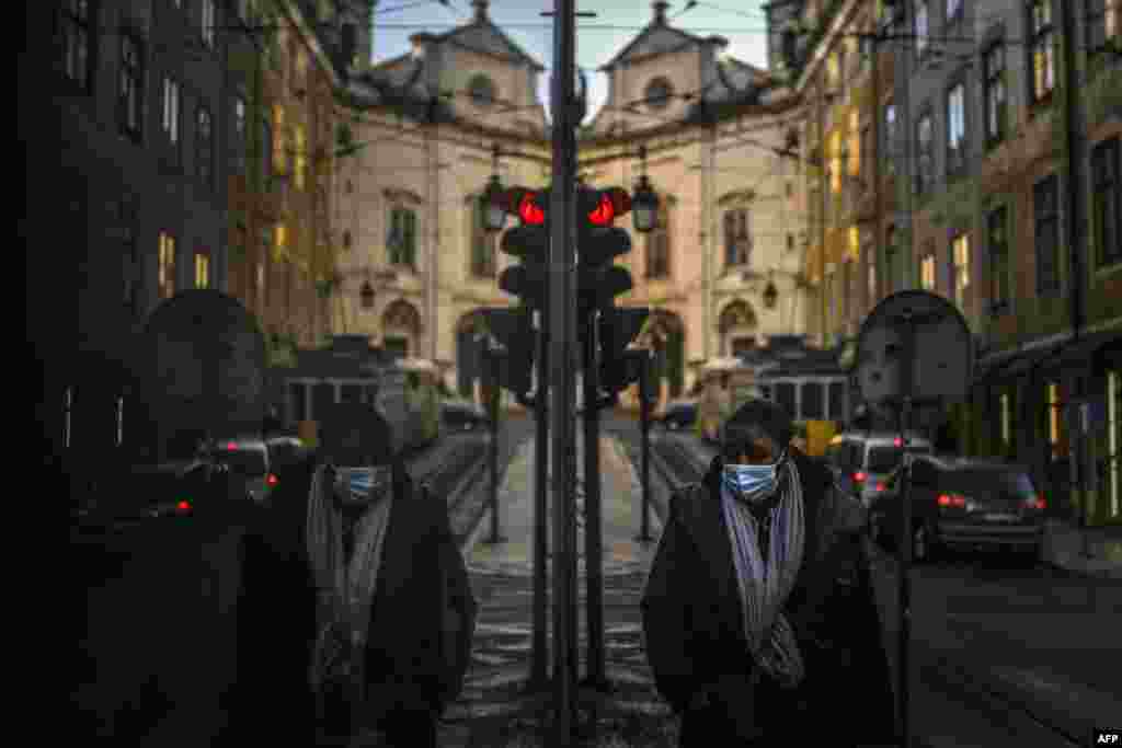 A woman wearing a face mask is reflected in a shop window while walking in Lisbon as Portugal entered a fresh lockdown over a surge in coronavirus cases.