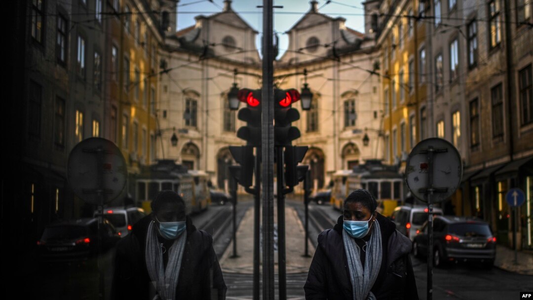 A woman wearing a face mask is reflected in a shop window while walking in Lisbon as Portugal entered a fresh lockdown over a surge in coronavirus cases.