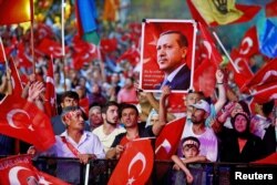 Supporters of Turkish President Recep Tayyip Erdogan wave national flags as they listen to him through a giant screen in Istanbul's Taksim Square, Turkey, Aug. 10, 2016.