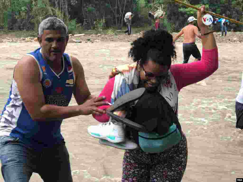 Un hombre ayuda a una mujer que cruza el río Táchira, en la frontera entre Colombia y Venezuela, el martes 2 de abril de 2019.