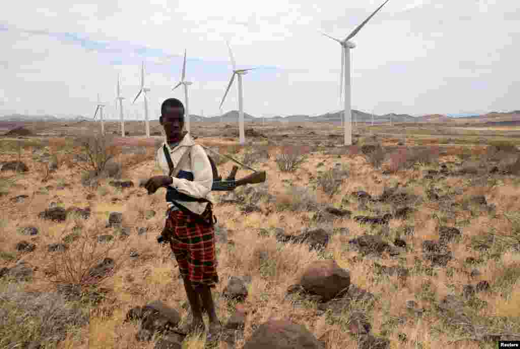A Turkana herdboy carries his rifle as he herds his goats near the power-generating wind turbines at the Lake Turkana Wind Power project (LTWP) in Loiyangalani district, Marsabit County, Kenya, Sept. 4, 2018.