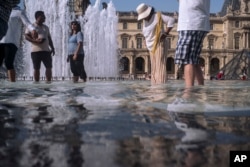 People cool off next to the fountains at Louvre Museum in Paris, July 24, 2019.