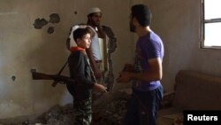 A 14-year-old fighter, whom activists say is the youngest in the Khadraa brigade operating under the Free Syrian Army, chats with his fellow fighters in Deir al-Zor, July 9, 2013. 