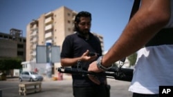 Men stand guard at an anti-Gadhafi checkpoint in downtown Tripoli, August 27, 2011