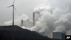 FILE - A wind turbine overlooks the coal-fired power station in Gelsenkirchen, Germany, Dec. 1, 2014. 