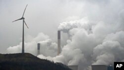 FILE - In this file photo dated Monday, Dec. 1, 2014, a wind turbine overlooks the coal-fired power station in Gelsenkirchen, Germany. 