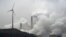 FILE - In this file photo dated Monday, Dec. 1, 2014, a wind turbine overlooks the coal-fired power station in Gelsenkirchen, Germany. 