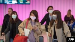 Passengers wear protective masks to protect against the spread of the Coronavirus as they arrive at the Los Angeles International Airport, California, on January 22, 2020. 