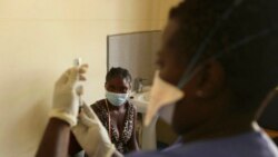 FILE - A young woman prepares to get vaccinated against COVID-19 at a health facility in Harare, Zimbabwe, Sept, 24, 2021.