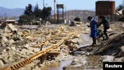 A couple walk next to a damaged railway line after a flood at Diego de Almagro, Chile, March 28, 2015. 