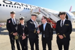 Dalam selebaran foto dari Qantas ini menunjukkan CEO Qantas Group Alan Joyce (C-R) berjabat tangan dengan pilot Qantas, Kapten Sean Golding (C-L) dengan kru di depan pesawat Qantas Boeing 787 Dreamliner. (Foto: AFP)