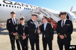 Dalam selebaran foto dari Qantas ini menunjukkan CEO Qantas Group Alan Joyce (C-R) berjabat tangan dengan pilot Qantas, Kapten Sean Golding (C-L) dengan kru di depan pesawat Qantas Boeing 787 Dreamliner. (Foto: AFP)