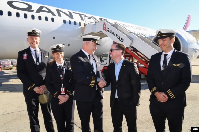 Dalam selebaran foto dari Qantas ini menunjukkan CEO Qantas Group Alan Joyce (C-R) berjabat tangan dengan pilot Qantas, Kapten Sean Golding (C-L) dengan kru di depan pesawat Qantas Boeing 787 Dreamliner. (Foto: AFP)