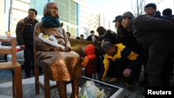 A flower is laid on a statue of a girl that represents the sexual victims by the Japanese military during a rally in front of Japanese Consulate in Busan, South Korea, Dec. 30, 2016. 