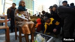 Sebuah bunga diletakkan pada sebuah patung seorang gadis yang mewakili korban seksual oleh militer Jepang saat berlangsungnya unjuk rasa di depan Jepang Konsulat di Busan, Korea Selatan, 30 Desember 2016. (Foto: dok).