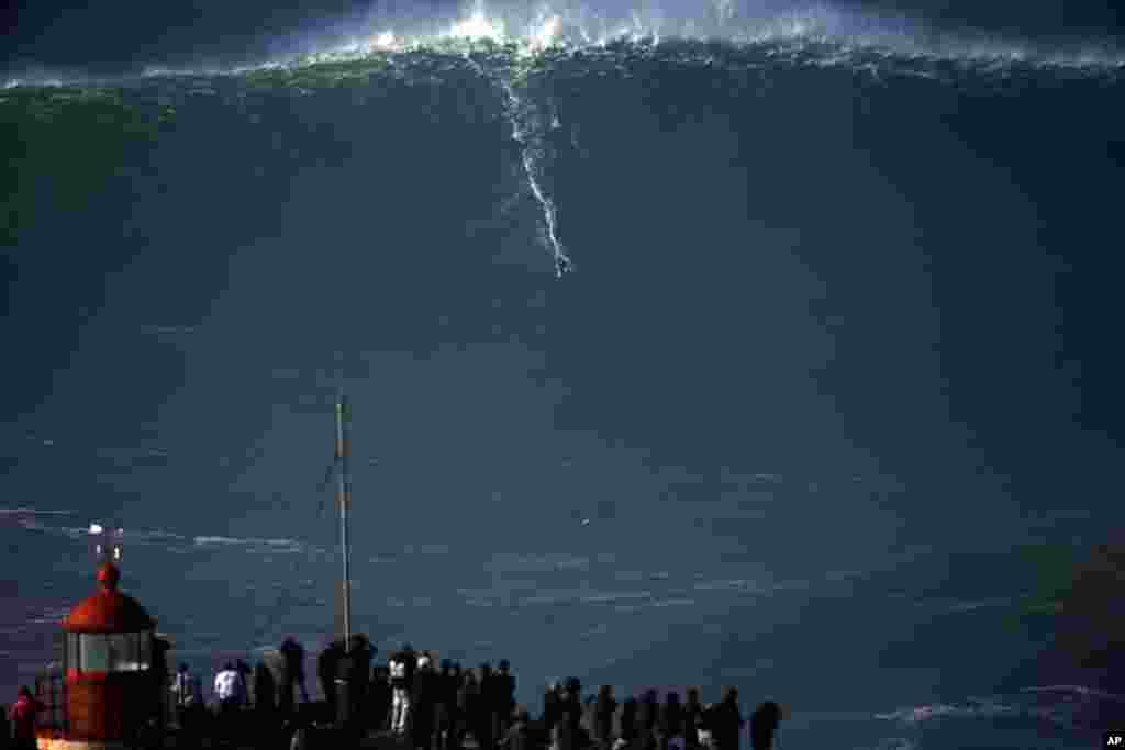 Một người lướt sóng cưỡi trên một con sóng khổng lồ ở Praia do Norte (Bãi biển Bắc), ở Nazare, Bồ Đào Nha.