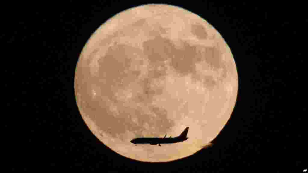 Un avion vole à coté la lune vu à Beijing, Chine, le 14 novembre 2016.