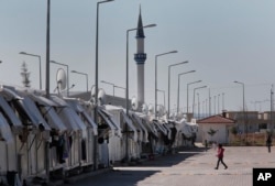 FILE - Refugees walk at the Oncupinar refugee camp for Syrian refugees next to the border crossing with Syria, near the town of Kilis in southeastern Turkey, Thursday, March 17, 2016.