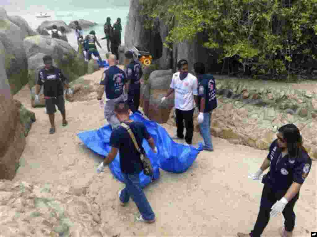Thai officers walk near the bodies of two British tourists Monday, Sept. 15, 2014 on a beach in Surat Thani province, southern Thailand. Their bodies were discovered early Monday on a beach on Koh Tao, a small island known for its diving sites and serene beaches, police said. (AP Photo/Daily News) 