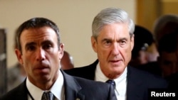 Công tố viên đặc biệt Robert Mueller (phải) rời đi sau khi báo cáo cho các thành viên Thượng viện Hoa Kỳ về cuộc điều tra của ông về sự thông đồng khả dĩ giữa ban vận động tranh cử của Donald Trump với Nga trong cuộc bầu cử tổng thống năm 2016