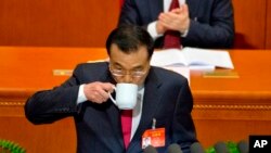 El primer ministro chino Li Keqiang bebe de la taza mientras entrega el informe de trabajo en la sesión de inauguración de la Asamblea Popular Nacional anual en el Gran Salón del Pueblo de Pekín, el domingo 5 de marzo de 2017.