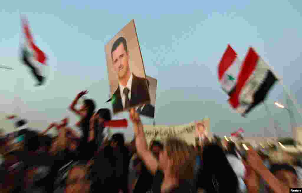 Jordanians and Syrians living in Jordan hold pictures of President Bashar al-Assad and shout slogans against the Syrian Revolution during a demonstration near the Syrian embassy in Amman July 19, 2012.