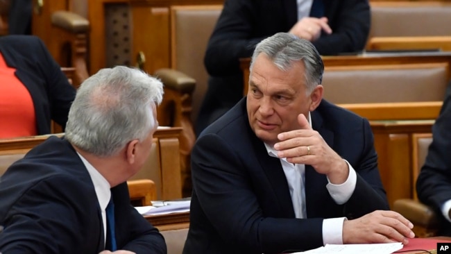 Hungarian Prime Minister Viktor Orban, right, chats with his deputy Zsolt Semjen during a plenary session of the Parliament in Budapest, Hungary, Budapest, Hungary, Monday, March 30, 2020. (Zoltan Mathe/MTI via AP)