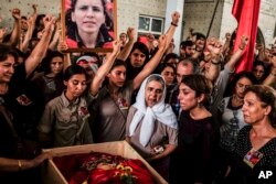 Mourners chant slogans as they gather around the body of Gulay Ozarlan, a DHKP-C militant, who was killed during a major police sweep that was launched against the outlawed group as well as suspected members of the outlawed Kurdish rebel group, and also Islamic State group militants, during her funeral In Istanbul, Turkey, July 25, 2015.