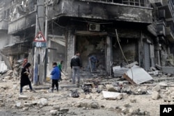 FILE - Syrian children remove rubble in the once rebel-held Bustan al-Qasr neighborhood in eastern Aleppo, Syria. Aleppo, Syria’s largest city, was widely brought to ruin by years of war, and now with Russia and Turkey leading peace efforts, international