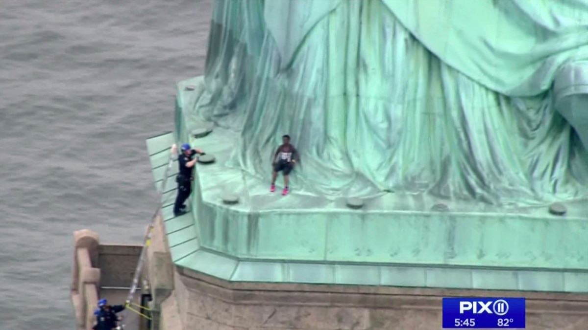 woman climbs statue of liberty