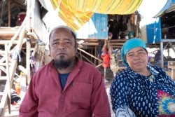 Y You, a 60 year-old representative of Khmer-Islam community, sits with his wife in front of his small house along the Chroy Changvar peninsular in Phnom Penh, Cambodia, on Nov. 30, 2019. (Tum Malis/VOA Khmer)