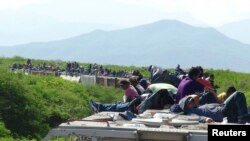 FILE - People hoping to reach the U.S. ride atop the wagon of a freight train, known as La Bestia (The Beast) in Ixtepec, in the Mexican state of Oaxaca, June 18, 2014. 