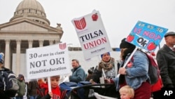 Keagan Nedrow, left, and Reed Nedrow, bottom right, stand with their mother, Tara Nedrow, right, who teaches history at Union High School, and other teachers, during a teacher rally against low school funding at the state Capitol Oklahoma City, Monday, Ap