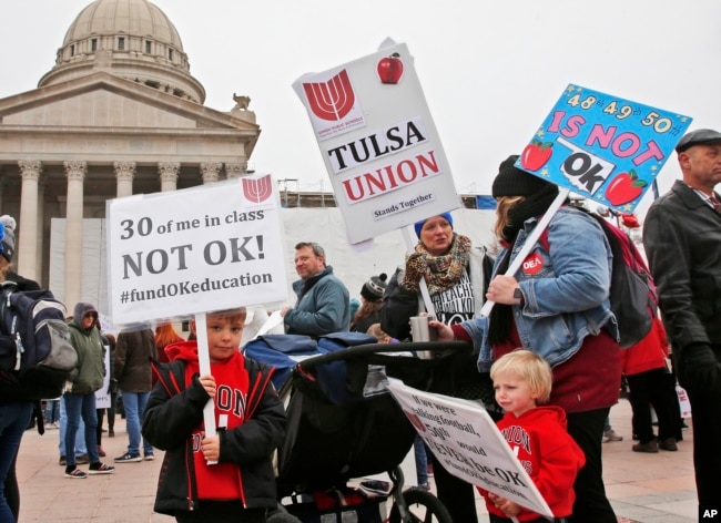 Keagan Nedrow, left, and Reed Nedrow, bottom right, stand with their mother, Tara Nedrow, right, who teaches history at Union High School, and other teachers, during a teacher rally against low school funding in Oklahoma City, Oklahoma. (AP Photo)