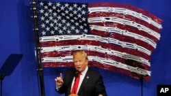 President Donald Trump speaks in front of an American flag made out of Snap-On Tools, Tuesday, April 18, 2017, in Kenosha, Wis. (AP Photo/Kiichiro Sato)