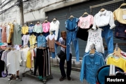 FILE - A street vendor holds his clothes when police take action on a street in Bangkok, Thailand, Sept. 12, 2018.