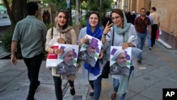 Supporters of Iranian President Hassan Rouhani hold posters with his image, May 17, 2017, during a street campaign ahead of Friday's presidential election in downtown Tehran, Iran.