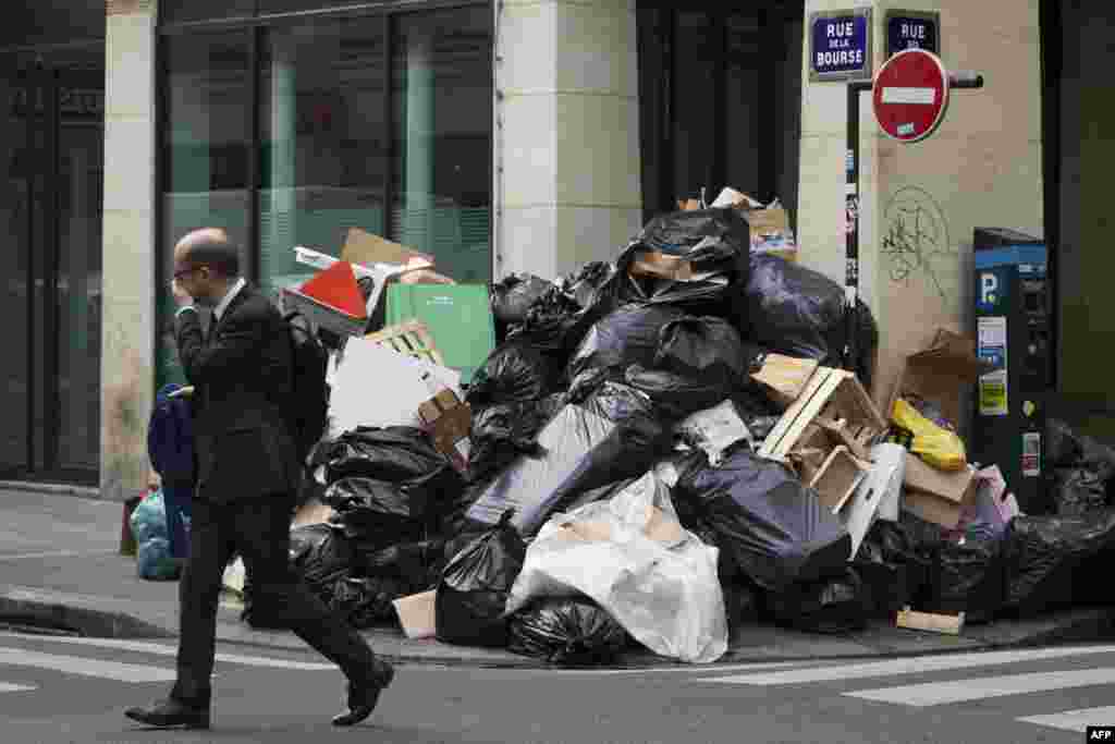 Seorang pria menutup hidungnya saat melewati tumpukan sampah di Paris, Perancis yang tidak dibersihkan akibat aksi pemogokan buruh.