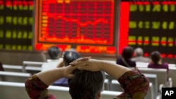 An investor watches a display of stock prices at a brokerage in Beijing, Aug. 21, 2015. 