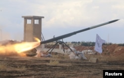 FILE - Rebel fighters from the First Regiment, part of the Free Syrian Army, fire a Grad rocket from Aleppo's al-Haidariya neighborhood, toward forces loyal to Syria's President Bashar al-Assad stationed in Talet al-Sheikh Youssef, Syria, May 29, 2016.