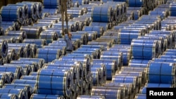 FILE - An employee works among stainless steel sheets at a steel factory in Taiyuan, Shanxi province, China, September 2, 2015.