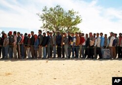 Bangladeshi migrant workers line up for food at the refugee camp 25km from the Libyan border.