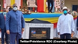 Perezida Félix Tshisekedi na Yoweri Museveni bahagaze iruhande rw'ibuye ry'ifatizo ry'umuhanda ibihugu byombi bihuriyeho ugiye kubakwa. 