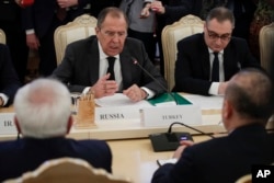 Russian Foreign Minister Sergey Lavrov, center, gestures while speaking to Turkey's Foreign Minister Mevlut Cavusoglu, right, back to a camera, and Iranian Foreign Minister Mohammad Javad Zarif, left, back to a camera, during their talks in Moscow, Russia.