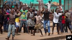 Angry supporters of opposition leader Kizza Besigye confront military police firing warning shots, near to his party headquarters, in Kampala, Uganda Friday, Feb. 19, 2016.