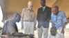 FILE - Former U.S. President Jimmy Carter, second from left, watches while a farmer with Guinea worm disease receives treatment from a volunteer trained by The Carter Center in partnership with the Government of Southern Sudan’s Guinea Worm Eradication Program, Feb. 11, 2010.